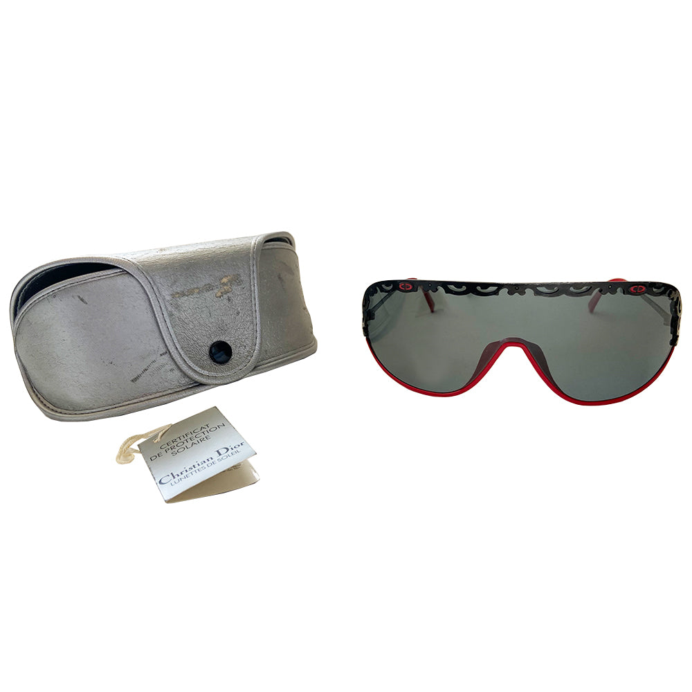 Christian Dior shield sunglasses circa 1980’s. Oversized shield lens with delicate black metal lace design along the top, with red accent metal rim at lower frame Vintage style Dior logo engraved on arms. Lens Color: Dark grey Style: 2501 93/110 Dior case included. Made in Austria