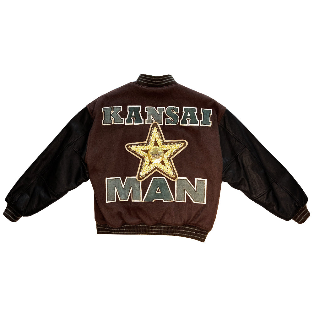 Kansai Man label 1980’s varsity jacket with black leather sleeves and brown wool body, leather accent slash pockets, rib knit collar, cuffs and bottom hem, logo front snap buttons. Super Stars varsity front appliqué lettering, Kansai Man in back with centre star. Full quilted lining, 2 inside slash pockets. Made in Japan