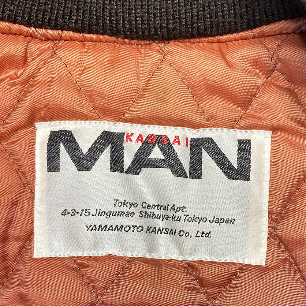 Kansai Man label 1980’s varsity jacket with black leather sleeves and brown wool body, leather accent slash pockets, rib knit collar, cuffs and bottom hem, logo front snap buttons. Super Stars varsity front appliqué lettering, Kansai Man in back with centre star. Full quilted lining, 2 inside slash pockets. Made in Japan