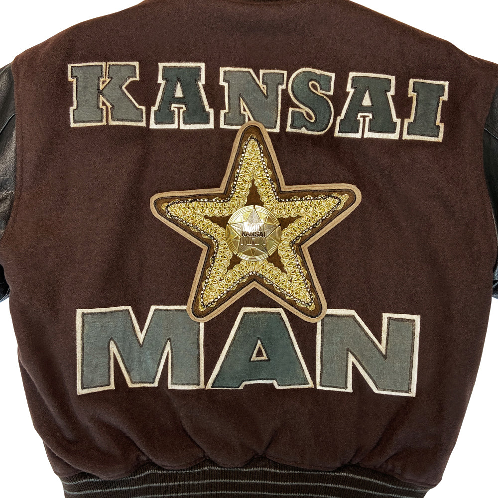Kansai Man label 1980’s varsity jacket with black leather sleeves and brown wool body, leather accent slash pockets, rib knit collar, cuffs and bottom hem, logo front snap buttons. Super Stars varsity front appliqué lettering, Kansai Man in back with centre star. Full quilted lining, 2 inside slash pockets. Made in Japan