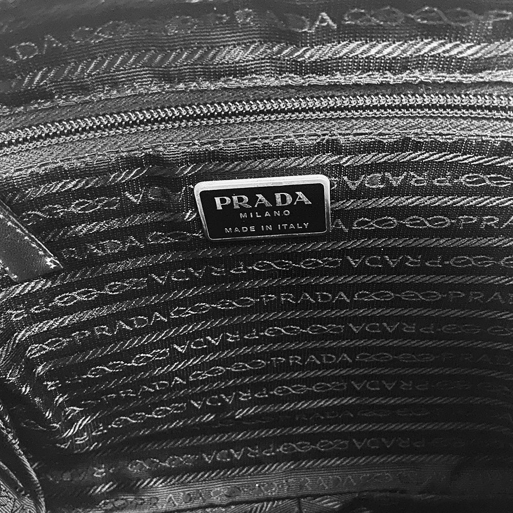 Prada spring 1999 RTW runway backpack in black and white tweed with black leather backing, adjustable leather harness straps, silver-tone hardware. Top zipper opens to jacquard logo textile lining with interior zip pocket. Made in Italy