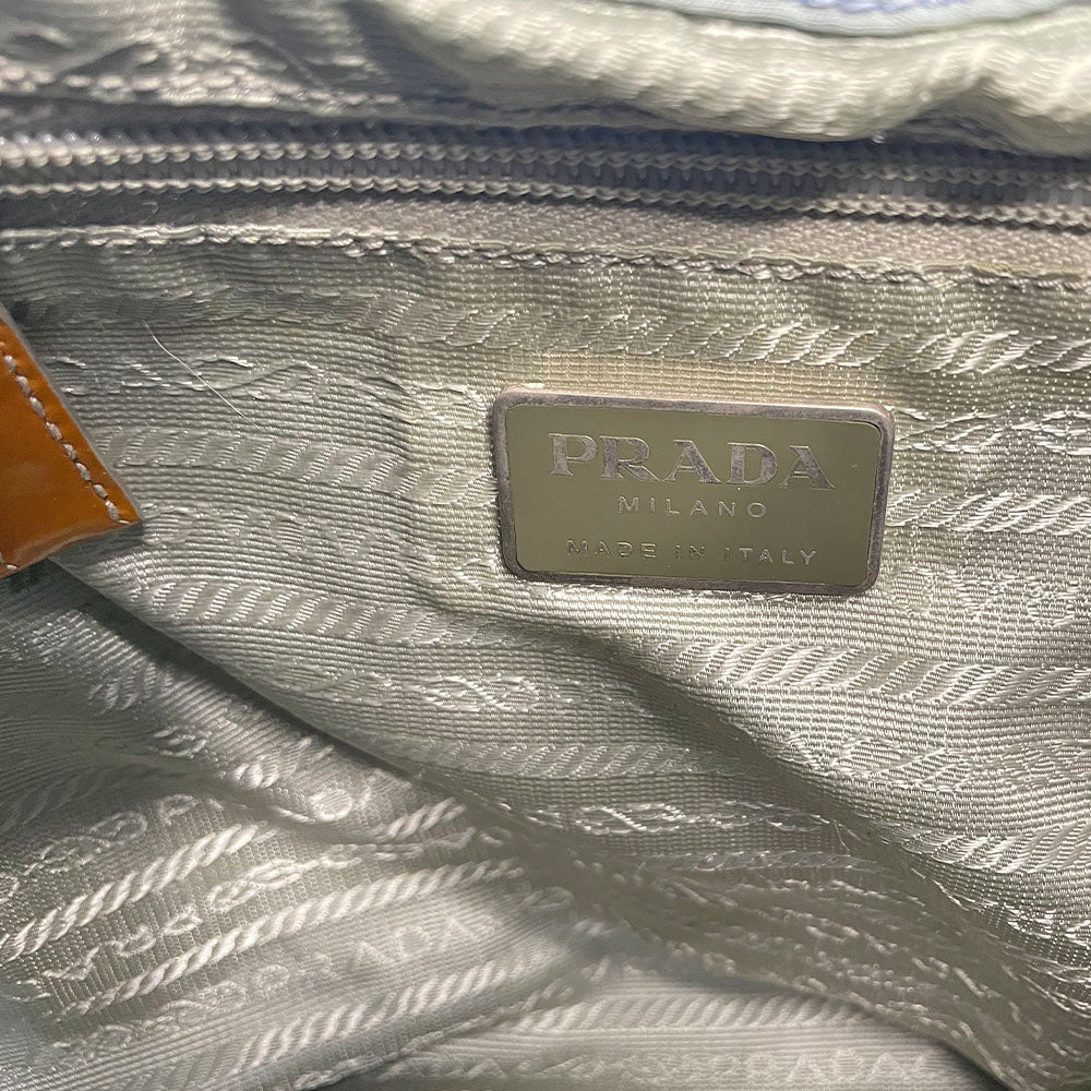 Prada powder blue nylon tessuto drawstring backpack circa 2011, magnetic closure flap with Prada logo plate, 2 zip outer front pockets, brown patent leather strap & accent, silver-tone Prada engraved buckle & drawstring grommets. Adjustable webbing & leather straps. Beige jacquard Prada logo textile lining with interior zip pocket. Made in Italy
