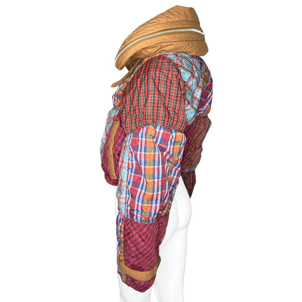 Tsumori Chisato long sleeved patchwork reversible hooded puffer jacket featuring a mix of madras & tartan fabrics with brown leather & canvas accent straps at wrists and pockets. Front zip closure with button, drawstring at waistline, puffy collar zips open to reveal hood. Reversible to all brown with zip-in tartan hood. Made in Japan