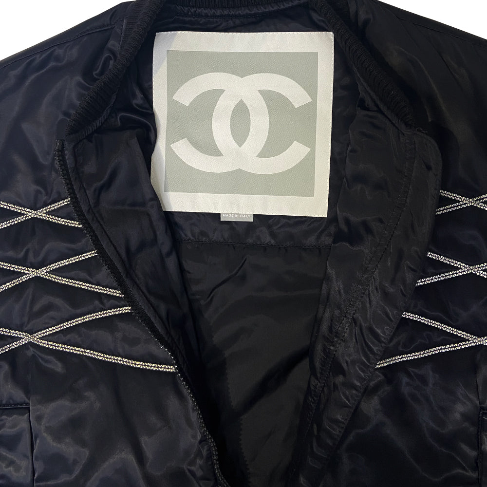 Chanel CC logo long sleeve black satin zip jacket by Karl Lagerfeld for Chanel, AW 2006 with side pockets, rib knit collar and cuffs, lamb leather accent, front zip, 2 buckle closure. CC engraved padlock zipper pull. White appliqué cording accents on front, back and sleeve with embroidered CC box logo, CHANEL in back, metal D-ring. Made in Italy 