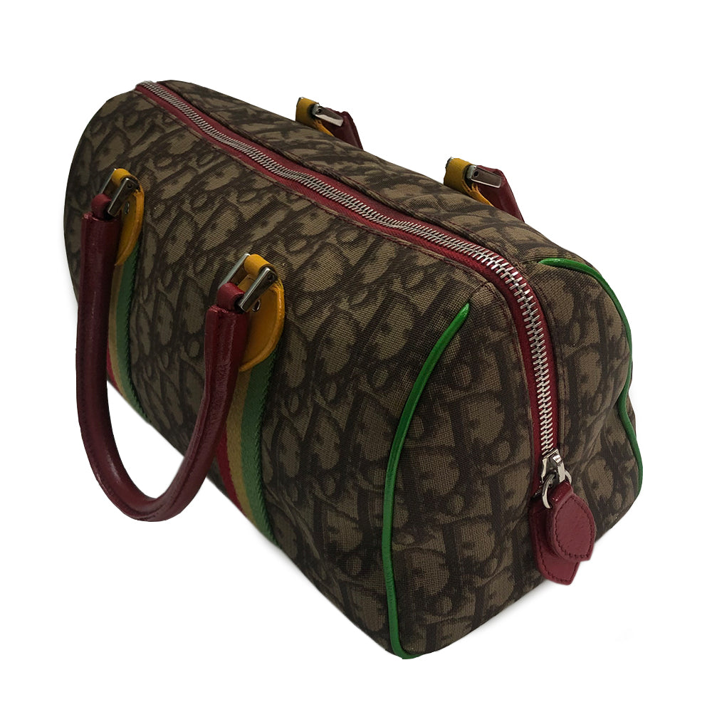 Christian Dior Rasta Boston Bag by John Galliano, 2003 beige and brown Diorissimo coated canvas, silver-tone hardware, vermillion leather rolled handles, yellow accent at base of handles. Yellow #1 front. Red, yellow and green canvas stripe on beige and brown Diorissimo print with bright green piping. Bottom domed silver-tone feet, single interior zip pocket and zip closure at top Vermillion textile interior, single zip pocket.