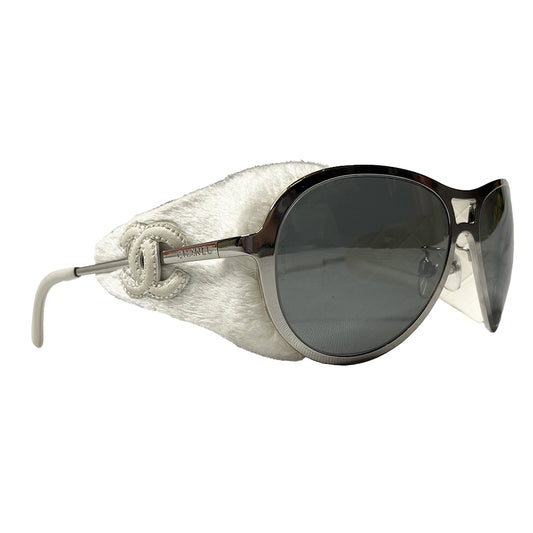 Very rare Chanel chrome and faux fur sunglasses by Karl Lagerfeld for Chanel  with oversized frames and Chanel engraved on side arms, dark gray lenses. Removable white faux fur side panel “blinders" with cream leather appliqué interlocking CC logo.  Model: 40852A Chanel case included. Made in Italy 