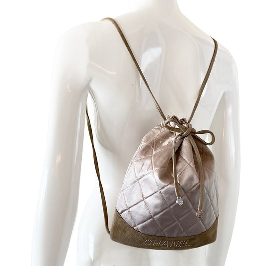 Chanel quilted satin soft backpack by Karl Lagerfeld for Chanel 2001 with suede  straps and suede drawstring closure, silver-tone Chanel stamped tips. Embedded faux pearls spell-out CHANEL on exterior suede. Satin interior with single slip pocket. Date code tag attached. Periwinkle satin with tan suede. Made in France 