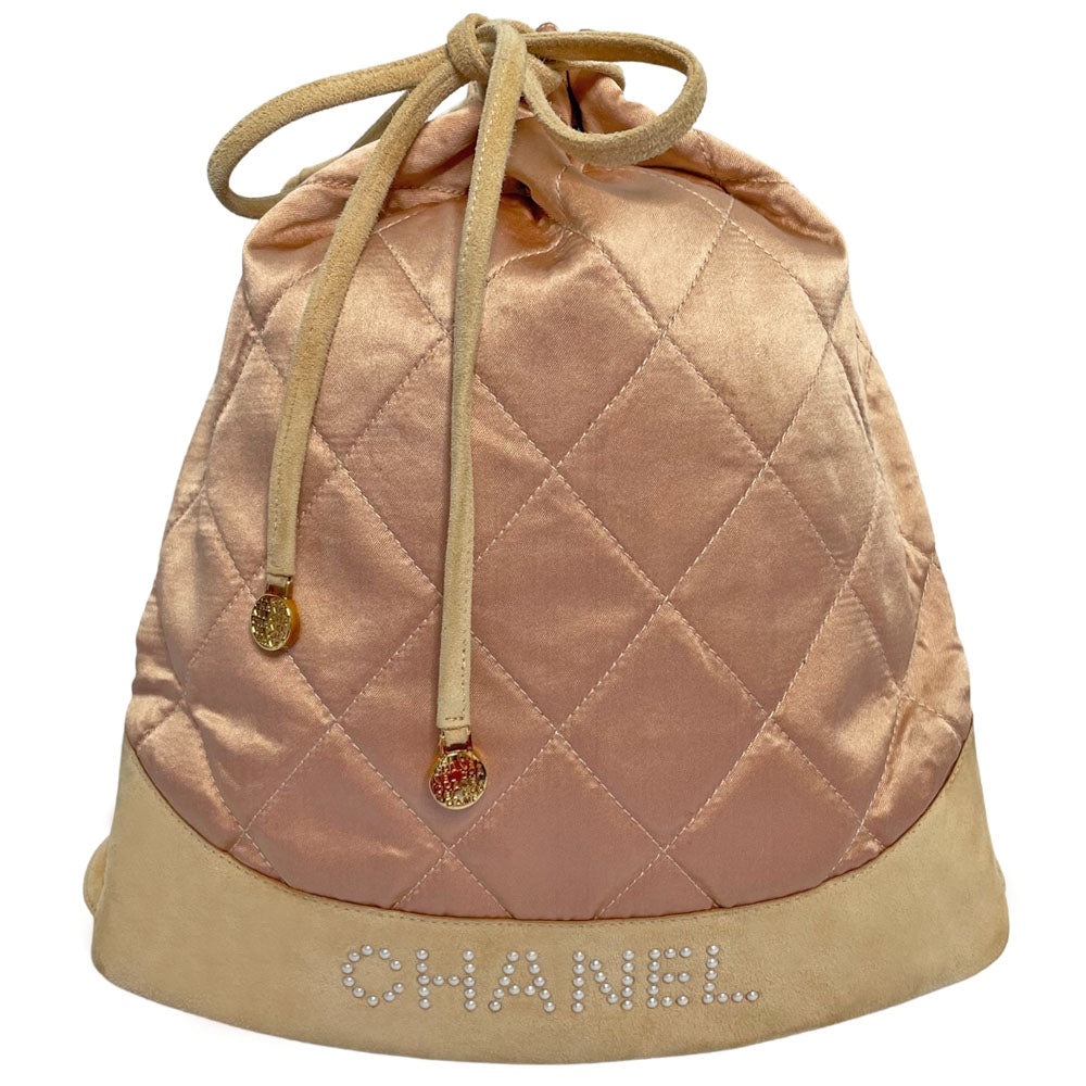 Chanel pink quilted satin and tan suede soft backpack by Karl Lagerfeld for Chanel 2001 with suede drawstring closure, silver-tone Chanel stamped tips and suede straps. Embedded faux pearls spell-out CHANEL embellishment on exterior suede satin interior with single slip pocket. Folds down flat. Made in France 