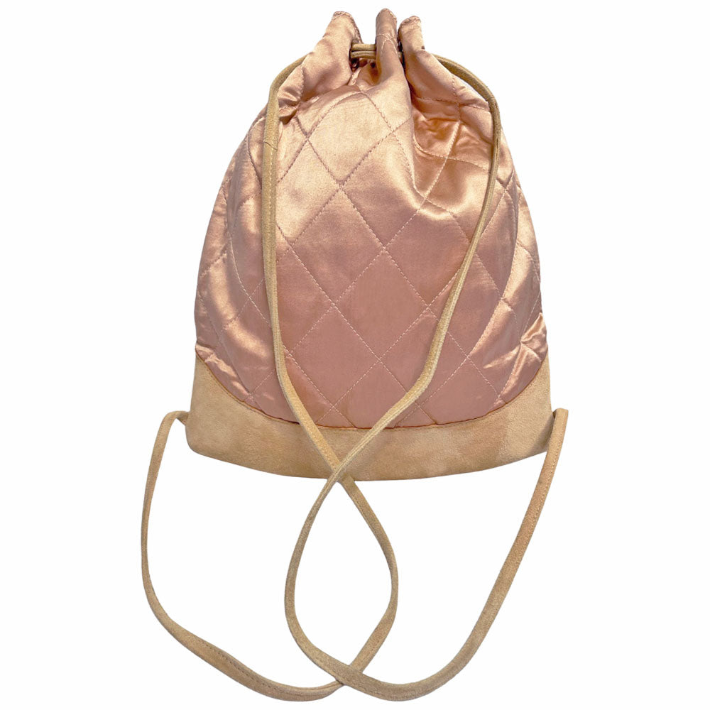 Chanel pink quilted satin and tan suede soft backpack by Karl Lagerfeld for Chanel 2001 with suede drawstring closure, silver-tone Chanel stamped tips and suede straps. Embedded faux pearls spell-out CHANEL embellishment on exterior suede satin interior with single slip pocket. Folds down flat. Made in France 