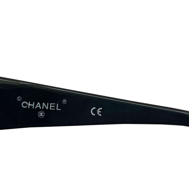 Chanel Paris CC logo black acetate frame sunglasses from the 1990’s by Karl Lagerfeld for Chanel embellished with gold-tone Chanel Paris engraved strip across the top from edge to edge and thick side arms and blue lenses. Style: 07798 94305. Made in Italy 