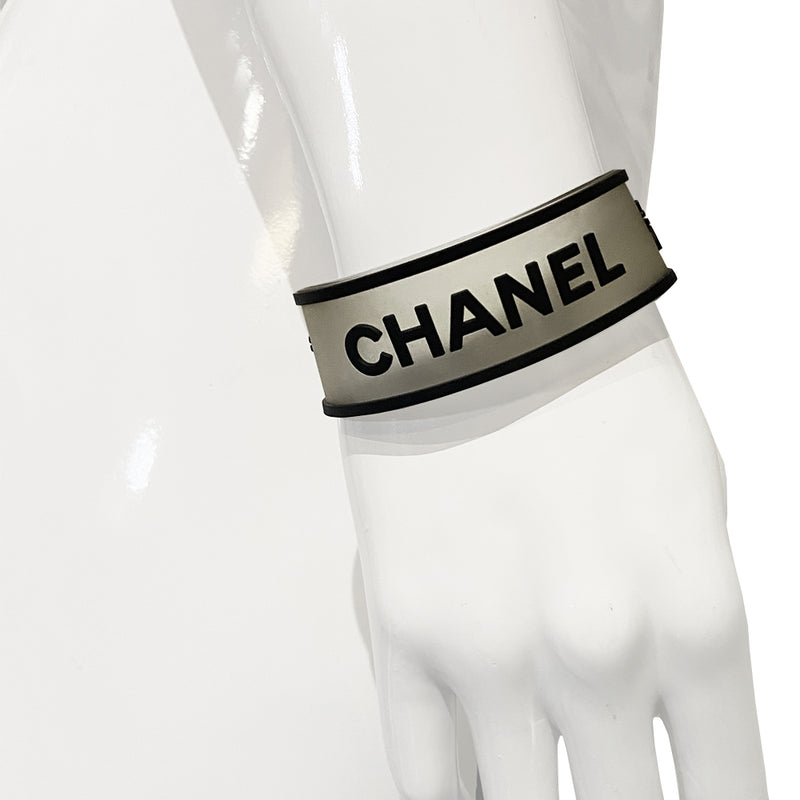 Chanel rubber bracelet by Karl Lagerfeld for Chanel, Autumn 2001 with translucent with black edges tinted rubber bracelet with CHANEL printed out and 2 clovers at each end in black. Silver-tone end caps and hook closure, Chanel hallmark makers mark stamp. Made in France 