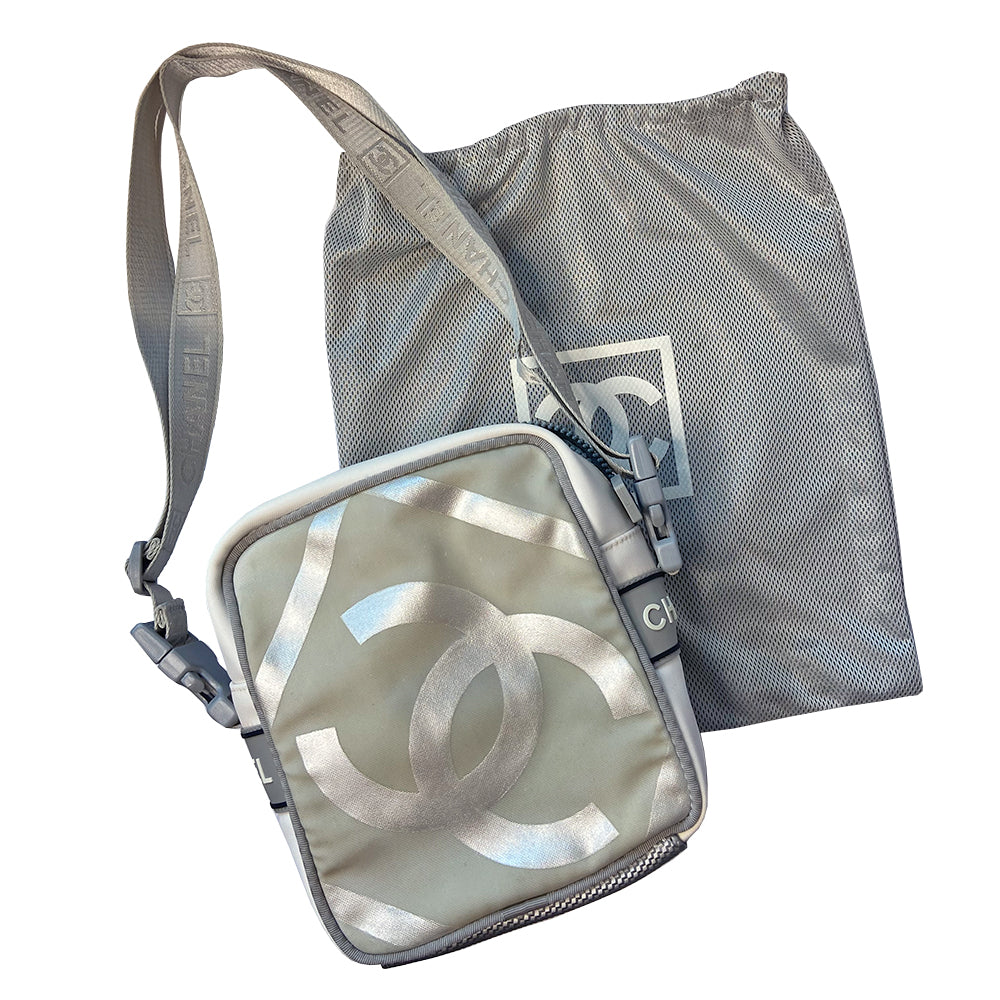 Chanel grey with silver Sport Line nylon canvas rectangular cross body messenger bag by Karl Lagerfeld for Chanel, 2001 with angled box front CC logo, rubber CHANEL side logos, grey piping and long sating webbing logo removable shoulder strap. Top ziper with grey textile interior and inside slip pocket. Made in Italy 