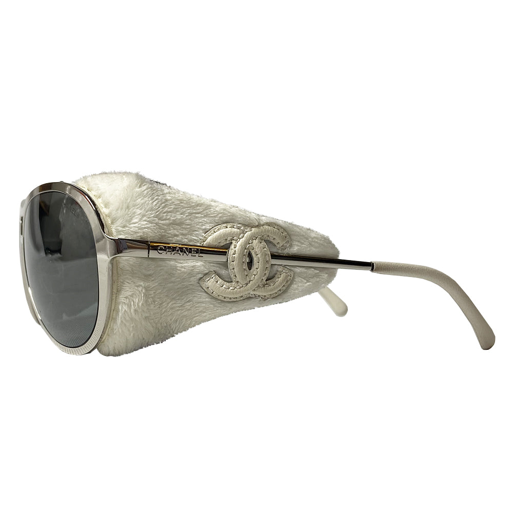 Very rare Chanel chrome and faux fur sunglasses by Karl Lagerfeld for Chanel  with oversized frames and Chanel engraved on side arms, dark gray lenses. Removable white faux fur side panel “blinders" with cream leather appliqué interlocking CC logo.  Model: 40852A Chanel case included. Made in Italy 