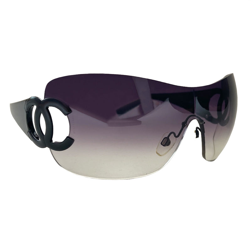 Chanel CC logo oversized shield frameless sunglasses with gradient lavender lens and black acetate arms. Black CC cutout black metal CC logo at side hinges. Style: 4124. Made in Italy 