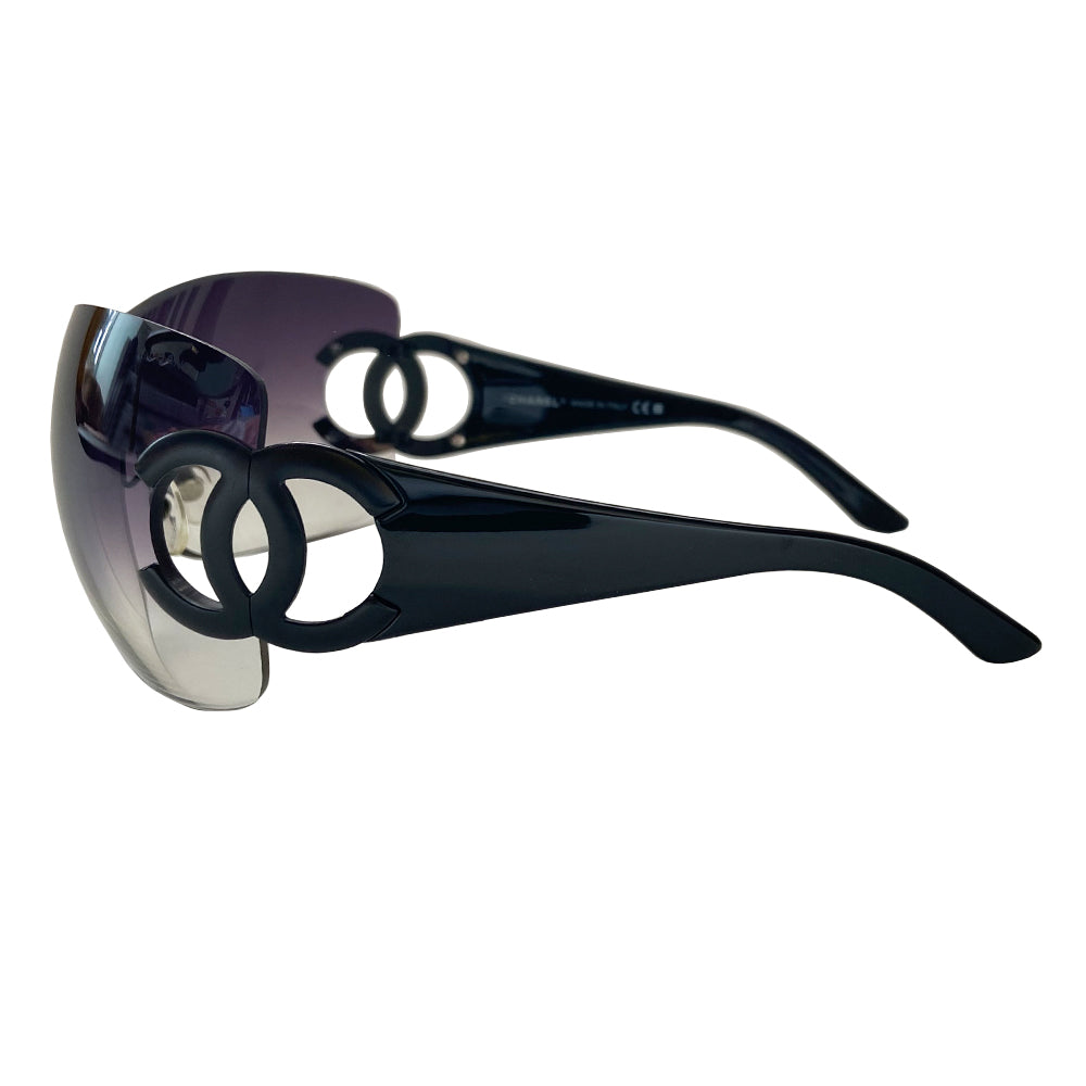 Chanel CC logo oversized shield frameless sunglasses with gradient lavender lens and black acetate arms. Black CC cutout black metal CC logo at side hinges. Style: 4124. Made in Italy 