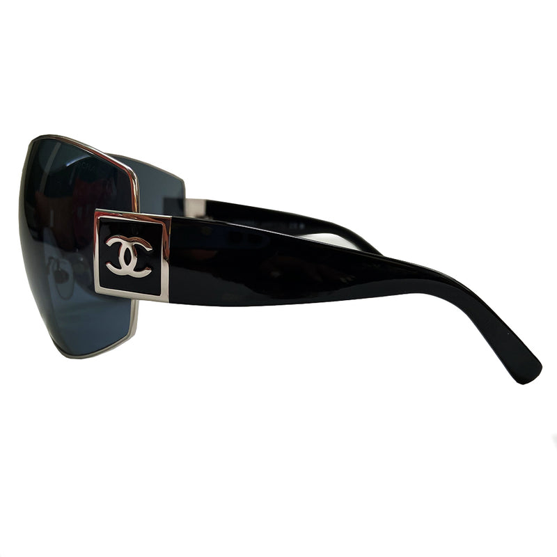 Chanel Oversized Shield Sunglasses with oversized lens surrounded by silver-tone metal frame, wide arms, square CC silver logo at sides that wrap on to the lens Condition: Excellent, no scratches on lens. Main Color: Black with black lens