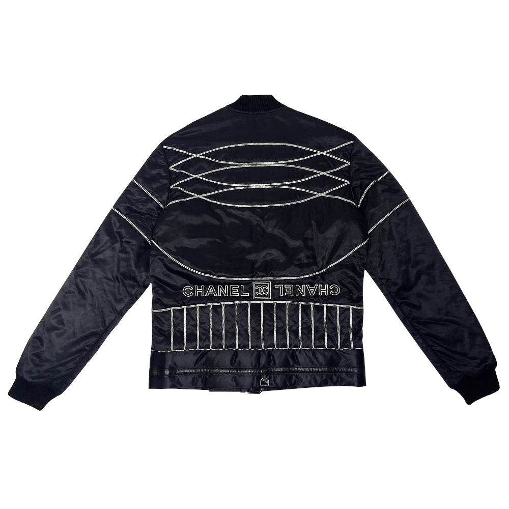 Chanel CC logo long sleeve black satin zip jacket by Karl Lagerfeld for Chanel, AW 2006 with side pockets, rib knit collar and cuffs, lamb leather accent, front zip, 2 buckle closure. CC engraved padlock zipper pull. White appliqué cording accents on front, back and sleeve with embroidered CC box logo, CHANEL in back, metal D-ring. Made in Italy 