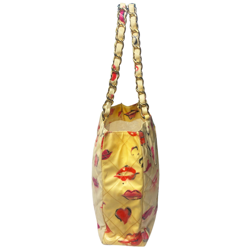 Chanel 1995 cream with printed red lips and hearts vinyl tote by Karl Lagerfeld for Chanel, double chain shoulder straps, oversized white interlocking front CC vinyl appliqué. Open top with interior cream color grosgrain lining, zippered pocket with gold-tone CC logo zipper pull, large slip pocket. Made in Italy 