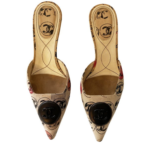 Chanel CC Logo Medallion slip-on heels from 2006 Karl Lagerfeld for Chanel. Pointed toe and all over CC logo printed fabric embellished with interlocking CC enamel logo on leather medallion. Black high-gloss heels, matching fabric heel pad at insoles, leather soles. Cream with red, grey and tan 