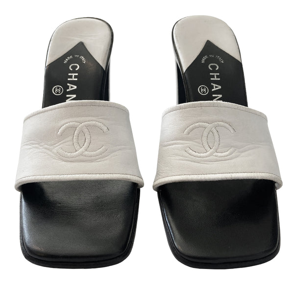 Chanel white square toe slip on mules with black leather covered block heels, leather upper with embroidered interlocking CC logo and edging. White and black leather insole with leather bottom sole. Made in Italy