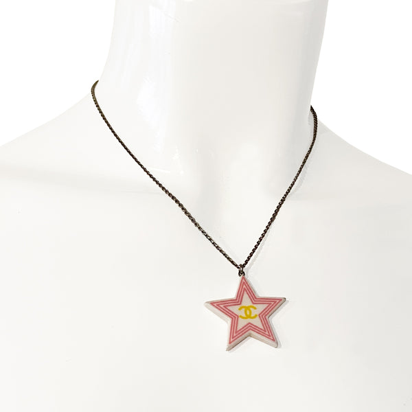 Chanel 2 sided white resin star pendant necklace by Karl Lagerfeld for Chanel Cruise collection, 2004 with pink border and yellow CC logo on one side, green logo on the other. Silver-tone long chain with lobster closure, interlocking metal CC logo charm at one end and metal stamped tag attached. Made in France.