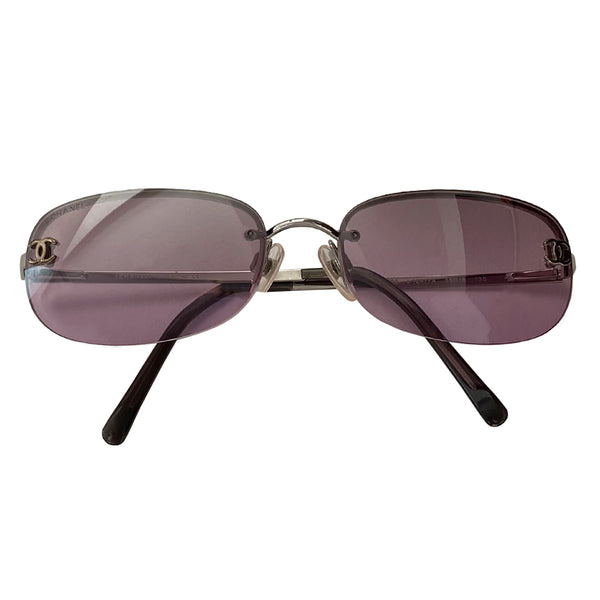 Chanel purple lens CC logo sunglasses with rounded rectangle shape, metal frame on upper lens and frameless on the bottom. Silver-tone metal frame with purple lenses, CC logo at each lens, Chanel engraved nose pad Includes case, box and dust cloth Style: 4099 C124/7A. Made in Italy 