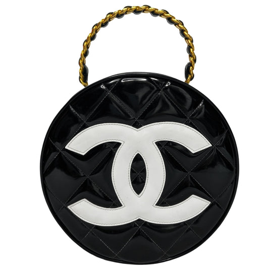 Chanel round diamond quilted black patent vanity case by Karl Lagerfeld for Chanel 1994-1996 with white interlocking appliqué CC logo at front, interwoven leather and gold chain top handle. Dual gold-tone zip around closure open to black leather interior with single slip pocket. Made in France 