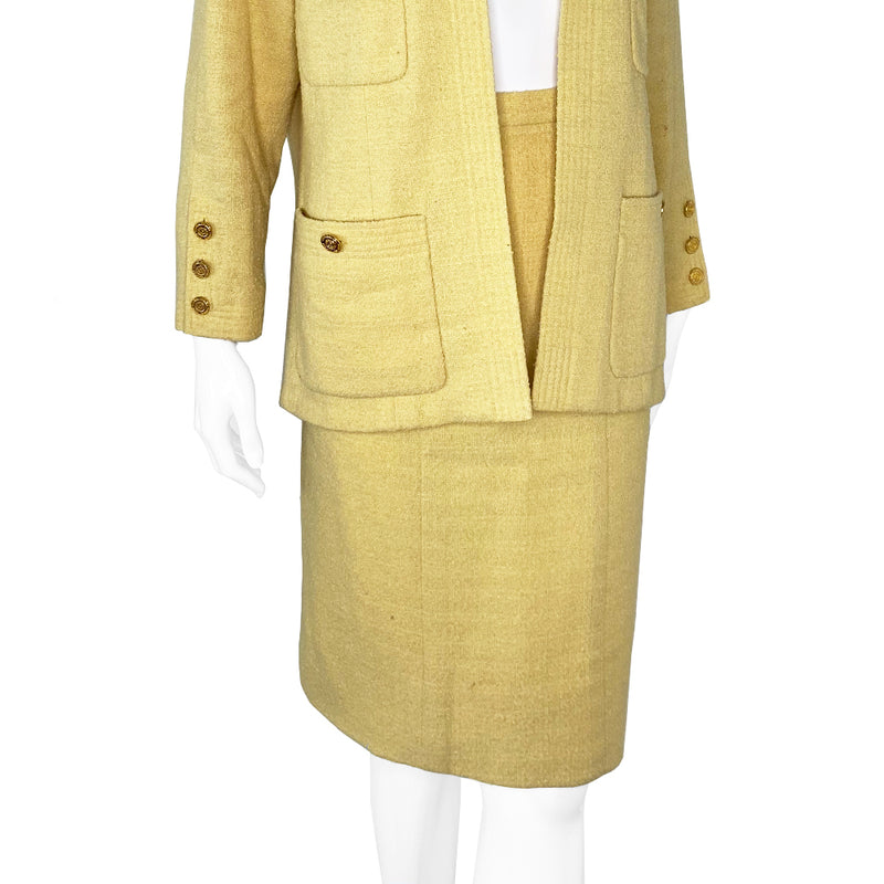 Chanel Boucle Jacket and Skirt Suit in Pale Yellow circa 1980’s in very good condition Jacket: Long sleeved with 4 pockets in front embellished with gold Chanel Rue Cambon logo buttons, 3 buttons at sleeves Skirt: Back invisible zipper with hook at waistband. Fabric: Main: 100%, Lining: 100% Silk. Made in France 