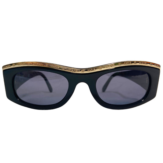 Chanel Paris CC logo black acetate frame sunglasses from the 1990’s by Karl Lagerfeld for Chanel embellished with gold-tone Chanel Paris engraved strip across the top from edge to edge and thick side arms and blue lenses. Style: 07798 94305. Made in Italy 