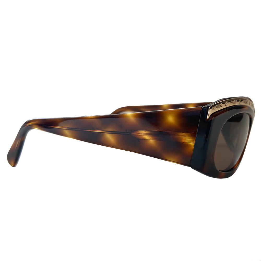 Chanel Paris CC logo tortoise sunglasses from the 1990’s, Karl Lagerfeld for Chanel. Tortoise acetate frames embellished with gold-tone Chanel Paris engraved strip across the top from edge to edge and thick side arms and dark brown lenses. Style: 07798 91235. Made in Italy
