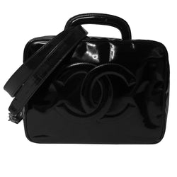 Chanel patent leather vanity case by Karl Lagerfeld for Chanel 1996 with interlocking CC logo at front, dual logo zipper pull closure, top carry handle and removable long strap. Leather interior with inner flap that snaps to side, zippered pocket with logo zipper pull, serial number sticker attached. Made in Italy