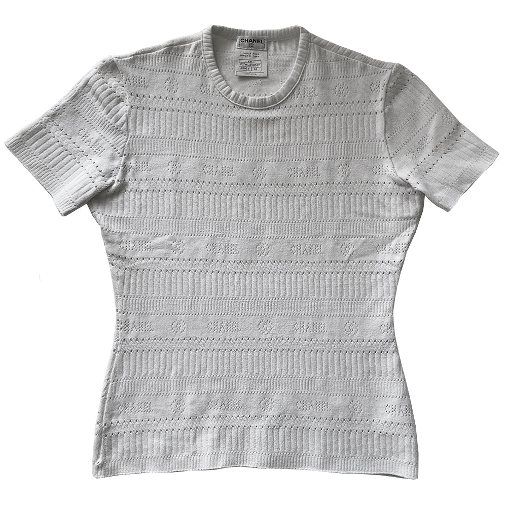 Chanel white ribbed perforated knit top by Karl Lagerfeld for Chanel, Spring 1997. Crew neck, all white short sleeved tee with perforations at ribbing edges and small woven diamond patterns to form horizontal stripes and 4 alternating rows of tiny perforations that form the word CHANEL. Made in France.