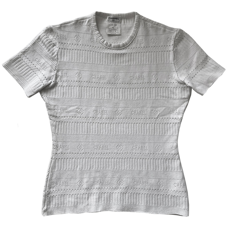 Chanel white ribbed perforated knit top by Karl Lagerfeld for Chanel, Spring 1997. Crew neck, all white short sleeved tee with perforations at ribbing edges and small woven diamond patterns to form horizontal stripes and 4 alternating rows of tiny perforations that form the word CHANEL. Made in France.