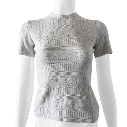 Chanel white ribbed perforated knit top by Karl Lagerfeld for Chanel, Spring 1997. Crew neck, all white short sleeved tee with perforations at ribbing edges and small woven diamond patterns to form horizontal stripes and 4 alternating rows of tiny perforations that form the word CHANEL. Made in France.