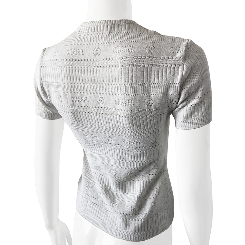Chanel white ribbed perforated knit top by Karl Lagerfeld for Chanel, Spring 1997. Crew neck, all white short sleeved tee with perforations at ribbing edges and small woven diamond patterns to form horizontal stripes and 4 alternating rows of tiny perforations that form the word CHANEL. Made in France.