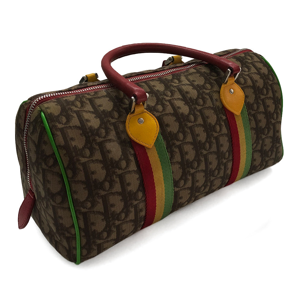 Christian Dior Rasta Boston Bag by John Galliano, 2003 beige and brown Diorissimo coated canvas, silver-tone hardware, vermillion leather rolled handles, yellow accent at base of handles. Yellow #1 front. Red, yellow and green canvas stripe on beige and brown Diorissimo print with bright green piping. Bottom domed silver-tone feet, single interior zip pocket and zip closure at top Vermillion textile interior, single zip pocket.