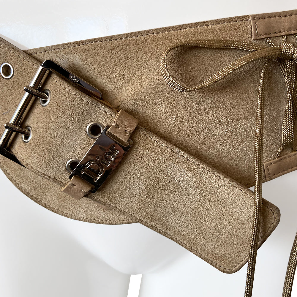 Christian Dior Suede Admit It lace-up corset belt in soft tan color from Autumn 2002 RTW collection by John Galliano. Criss-cross lace up detail with woven corset laces with silver aglet-tipped ends. Silver-tone double pronged buckle and Dior logo plate at front with adjustable sizing. Made in Italy 