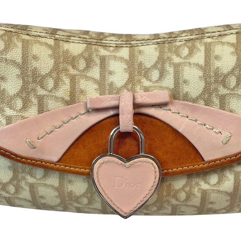 Christian Dior beige monogram coated canvas small shoulder bag by John Galliano for Dior, 2007 with brown leather piping, magnetic front flap, brown leather & pink leather bow detail with Dior logo embossed pink leather covered hanging heart. Blush rose satin lining, one zipper pocket. Pink leather woven through silver tone chain with brown leather strap. Made in Italy
