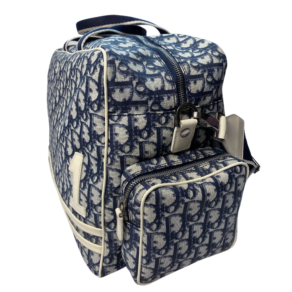 John Galliano for Dior, 2002 navy monogram canvas large weekender bag with 2 outer zip end pouches, velcro rear pocket, white patent leather piping, zipper pulls, No 1 appliqué in front and 2 accent stripes in front. Double canvas handles, detachable, adjustable navy carry strap. Silver-tone zipper and hardware, navy nylon lining with zippered pocket, two snap slip pockets, 3 open pouch pockets. Made in Italy 