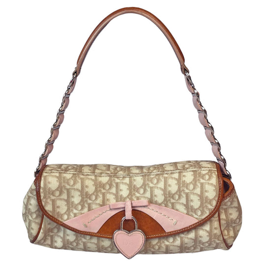 Christian Dior beige monogram coated canvas small shoulder bag by John Galliano for Dior, 2007 with brown leather piping, magnetic front flap, brown leather & pink leather bow detail with Dior logo embossed pink leather covered hanging heart. Blush rose satin lining, one zipper pocket. Pink leather woven through silver tone chain with brown leather strap. Made in Italy