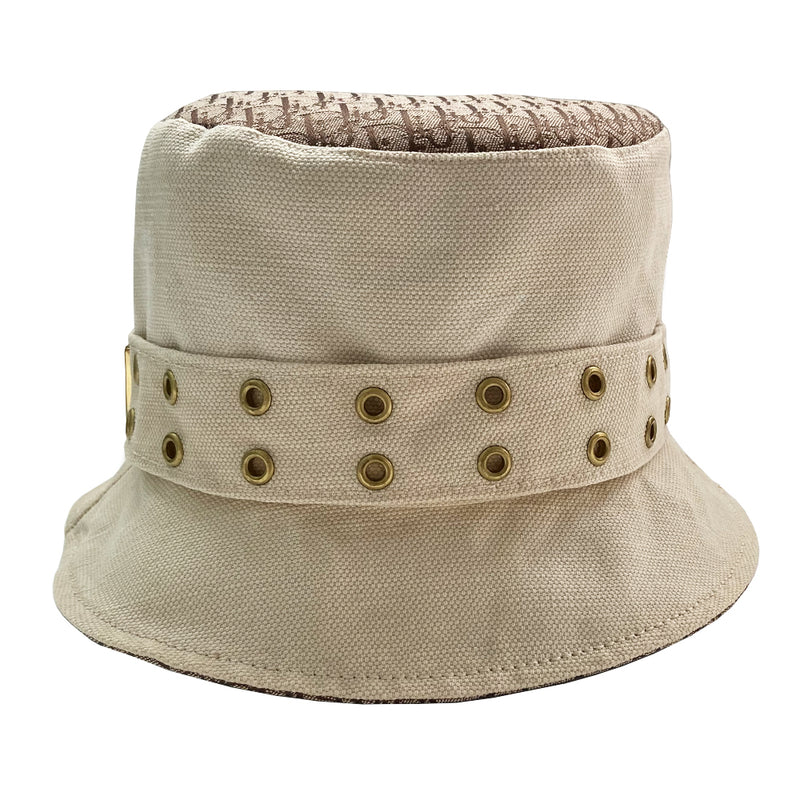 Christian Dior Street Chic Diorissimo Bucket Hat, S/S 2002 Street Chic collection by John Galliano. Light cream color canvas with tonal stitching and Diorissimo monogram logo fabric on top and under brim. Exterior band with antique brass-tone grommets and gold-tone pouch attachment and gold-tone Dior logo dog tag. Made in France 