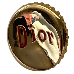 Christian Dior Logo Bottle Cap ring circa 2004. Gold-tone "bent” bottle cap ring with red embossed logo and thick band. Adjustable band for various sizing. Dior box and booklet included. 