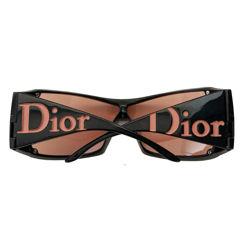 Christian Dior Overshine 2 Sunglasses circa early to mid 2000’s with oversized rose tint lenses, squared rims, black colored frame with wide arms. Dior logo name embossed in pink at each arm. Style: 00DX3 110. Made in Italy 