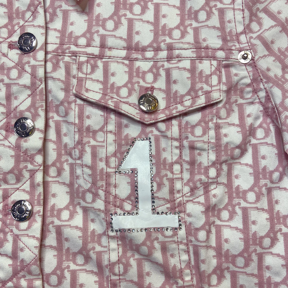 Christian Dior pink monogram Girly button up denim jacket by John Galliano for Dior, spring 2004 with 2 front flap pockets at chest and No 1 surrounded by Swarovski crystals. Silver-tone logo buttons and engraved logo buckle details on adjustable side straps, Dior crystal logo at one sleeve cuff. Made in Portugal 