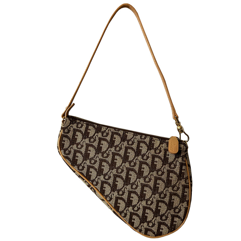 Christian Dior brown monogram canvas mini saddle pochette by John Galliano for Dior, 2001 with tan leather piping and strap with gold-tone hardware. Leather strap unclips at one end and can be looped to carry wristlet style. Top zip closure with Dior embossed leather zipper pull, brown textile interior. Made in Spain 