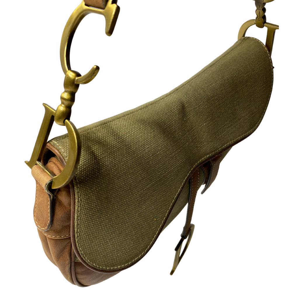 Christian Dior khaki canvas saddle bag by John Galliano for Dior 2002 with burnished gold-tone hardware, brown leather accent. Single flat top leather handle with CD logo adornments at each side. Velcro at flap closure with feature gold-tone D logo. Rear single slip pocket. Black/grey logo textile lined with zip pocket. Made in Italy 