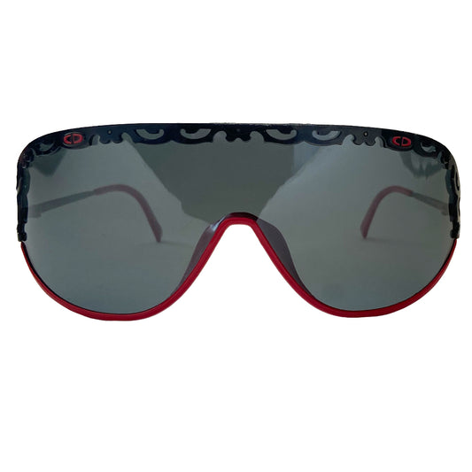 Christian Dior shield sunglasses circa 1980’s. Oversized shield lens with delicate black metal lace design along the top, with red accent metal rim at lower frame Vintage style Dior logo engraved on arms. Lens Color: Dark grey Style: 2501 93/110 Dior case included. Made in Austria 