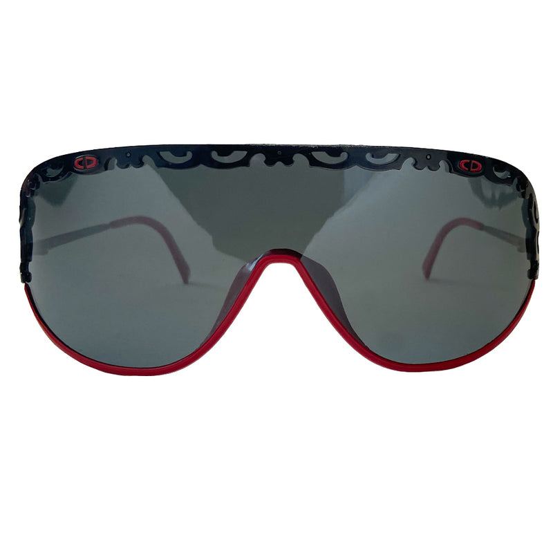 Christian Dior shield sunglasses circa 1980’s. Oversized shield lens with delicate black metal lace design along the top, with red accent metal rim at lower frame Vintage style Dior logo engraved on arms. Lens Color: Dark grey Style: 2501 93/110 Dior case included. Made in Austria 