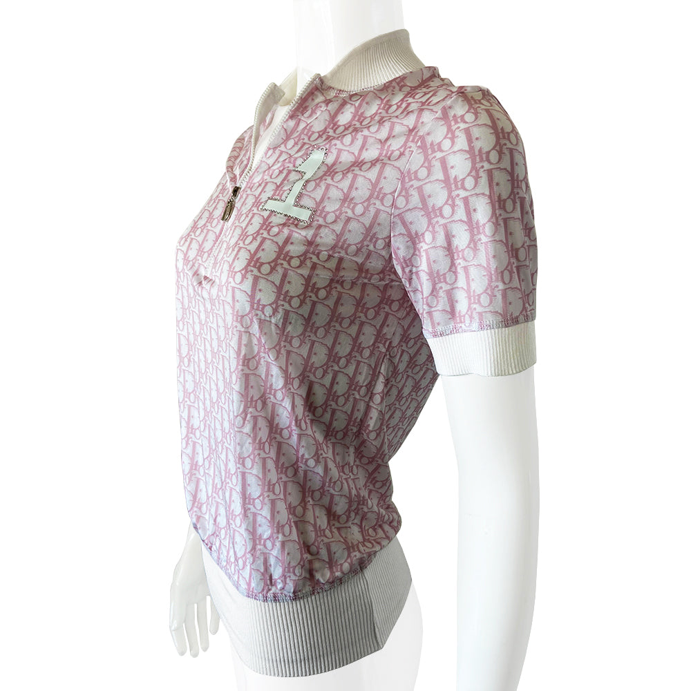Christian Dior pink Diorissimo No. 1 short sleeve zip sweater circa 2004 by John Galliano for Dior. Front zip Diorissimo print silky feel top with with wide accent ribbing at neckline, arm hems and bottom hem. No. 1 surrounded with white crystals at upper chest. Excellent condition. Made in France 