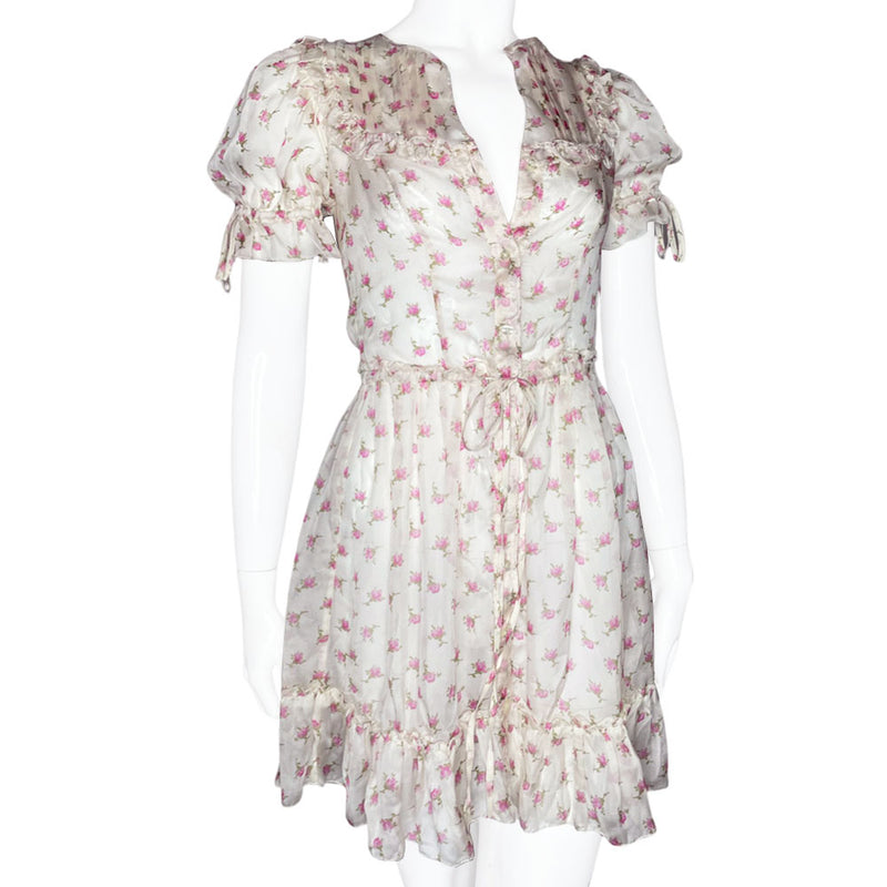 D&G silk pink and white puffed sleeve dress with D&G logo stamped button front in all over pink rosebud print. Ruffled yoke in front, back and hemline, elastic and ties at sleeves and waist. Made in Morocco 